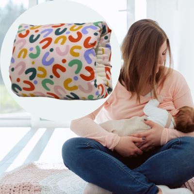 Maman qui allaite au sein son bébé assis confortablement avec coussin allaitement bariolé