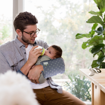Le papa qui donne le biberon à son bébé avec le coussin allaitement