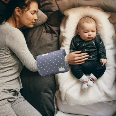 Maman qui cùline son bébé sur le lit aprÚs le biberon avec le coussin allaitement