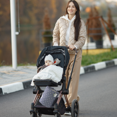Maman qui promène son bébé avec le coussin allaitement couronne dans la poussette