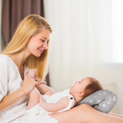 Maman qui joue avec son bébé sur ses genoux, accompagné du coussin d-allaitement astre