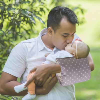 Papa qui porte son bébé avec au bras coussin d'allaitement astre