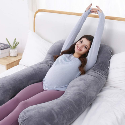 Une maman qui s'Ă©tire en souriant aprĂšs ĂȘtre bien reposĂ©e dans son coussin de grossesse.