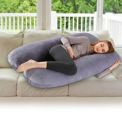 Une maman qui dort dans son canape avec le coussin de grossesse.