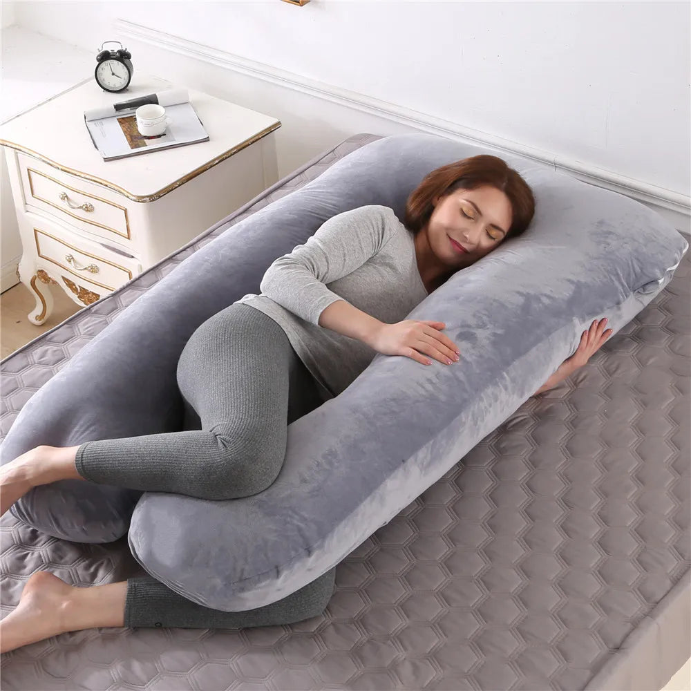 Un coussin de grossesse avec une femme allongee sur un lit, détendue et confortable, avec un leger sourire.