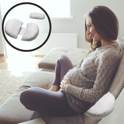 Maman qui est assise dans son canapé et qui utilise son coussin de grossesse pour le dos