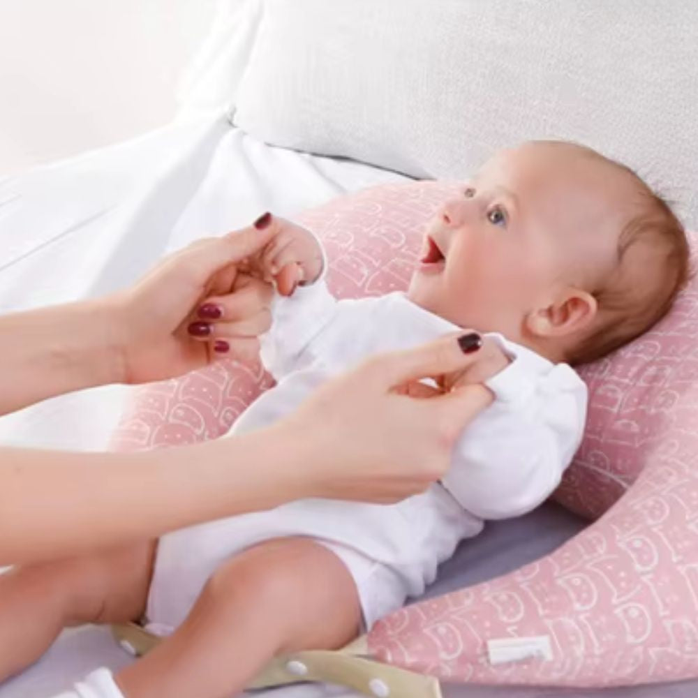 maman redresses son bebe sur le coussin d'allaitement