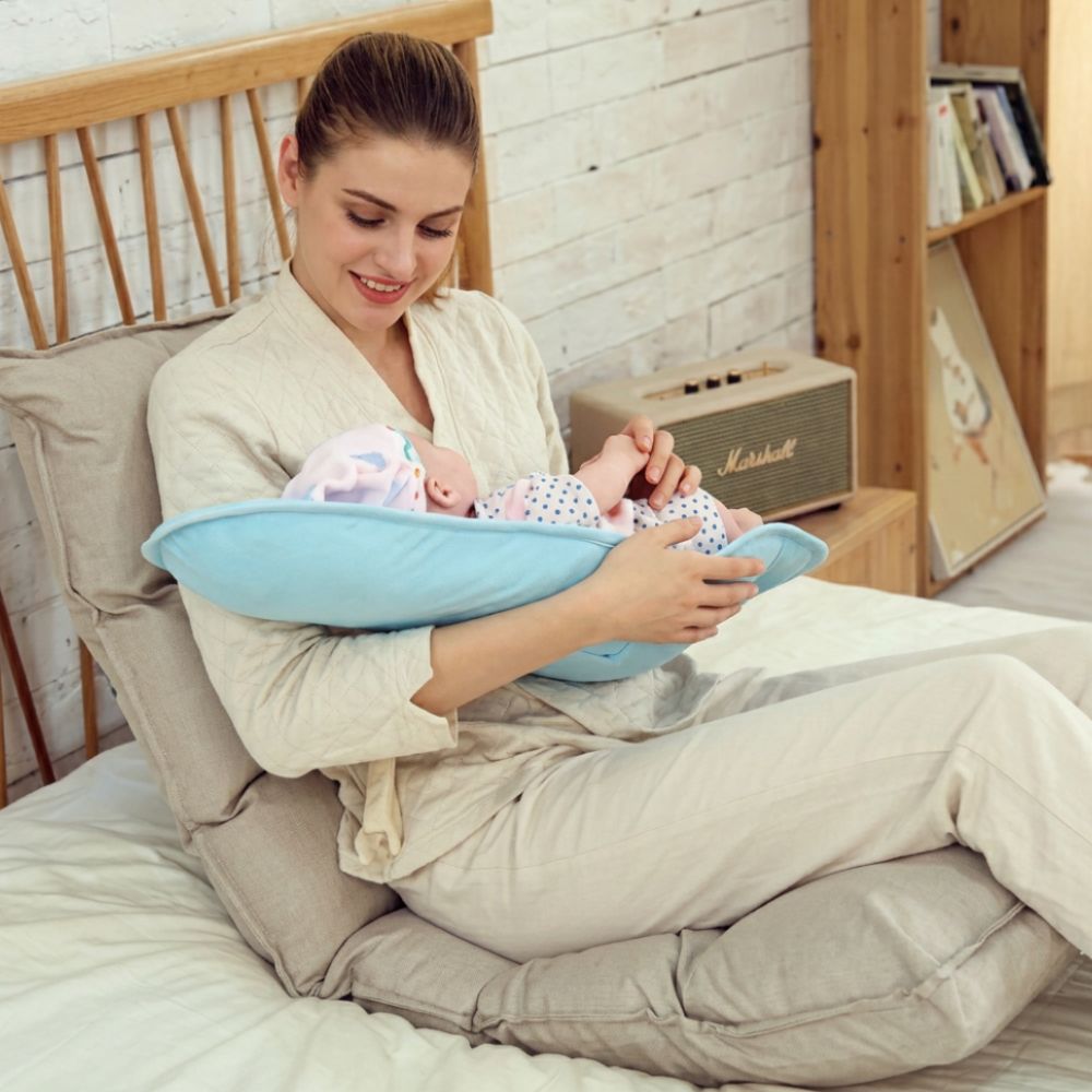 Coussin allaitement bleu dans le bras de maman caler dans son lit