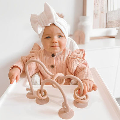 Anneau de dentition rose avec enfant assis chaise haute