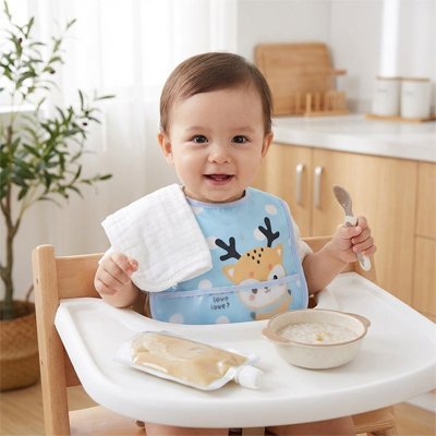 Bavoir pour bebe assit devant son bol de lait