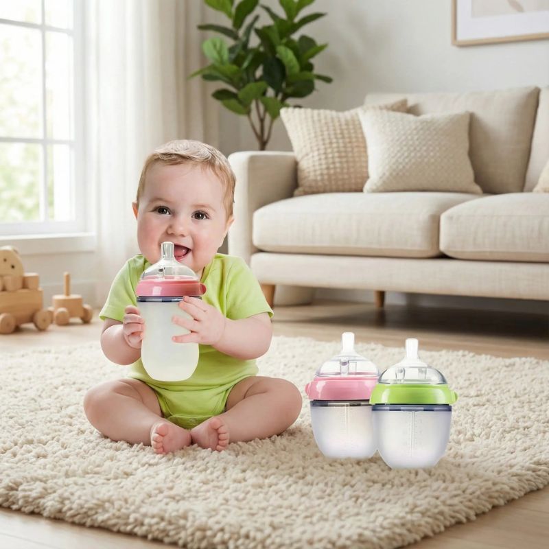 bebe assise tapis avec son biberon anis vert