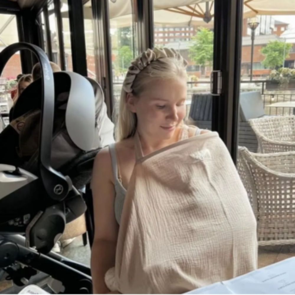 cape d'allaitement beige maman  au restaurant avec son bébé