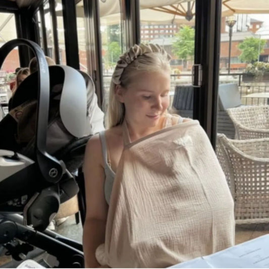 cape d'allaitement beige maman  au restaurant avec son bébé