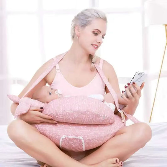 maman sur son telephone avec le coussin d'allaitement et bebe
