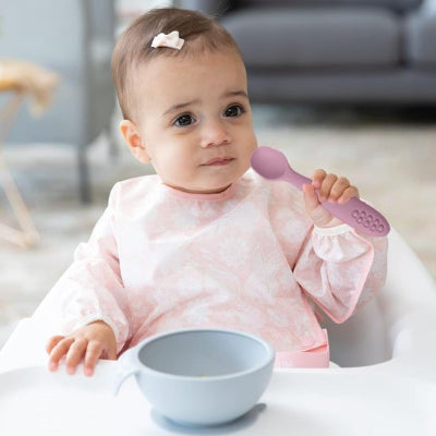 Cuillere bebe assit devant son bol bleu