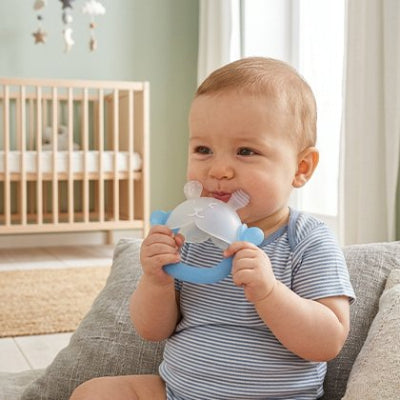 enfant assis dans canape avec son anneau de dentition bébé