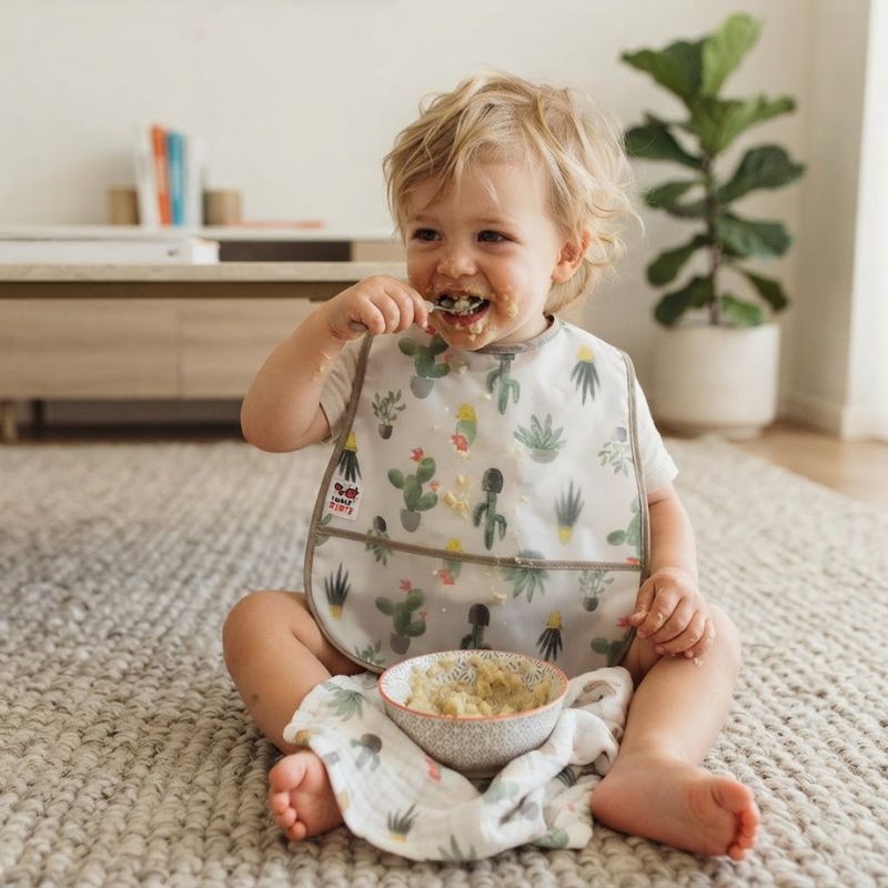 enfant asssie sur le tapis et mange Bavoir bebe Ultra-absorbant