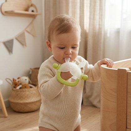 enfant debout avec son anneau de dentition bébé